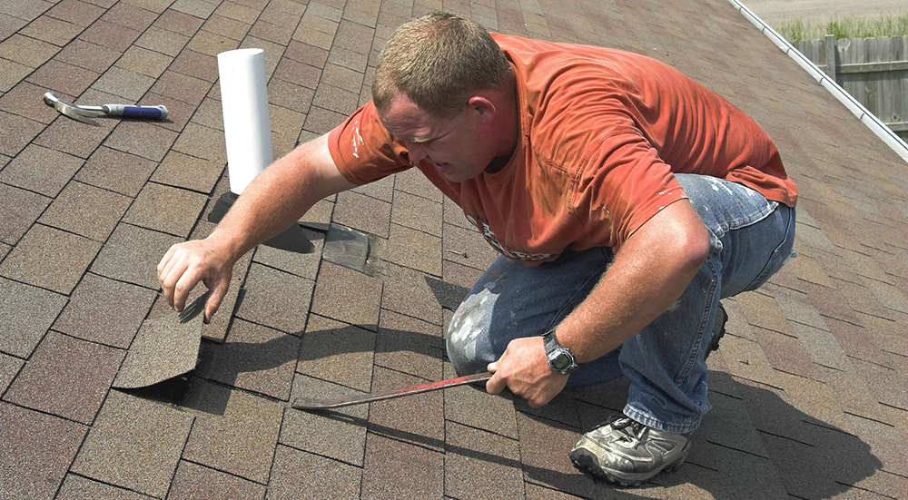 Roofer fixing shingle on roof
