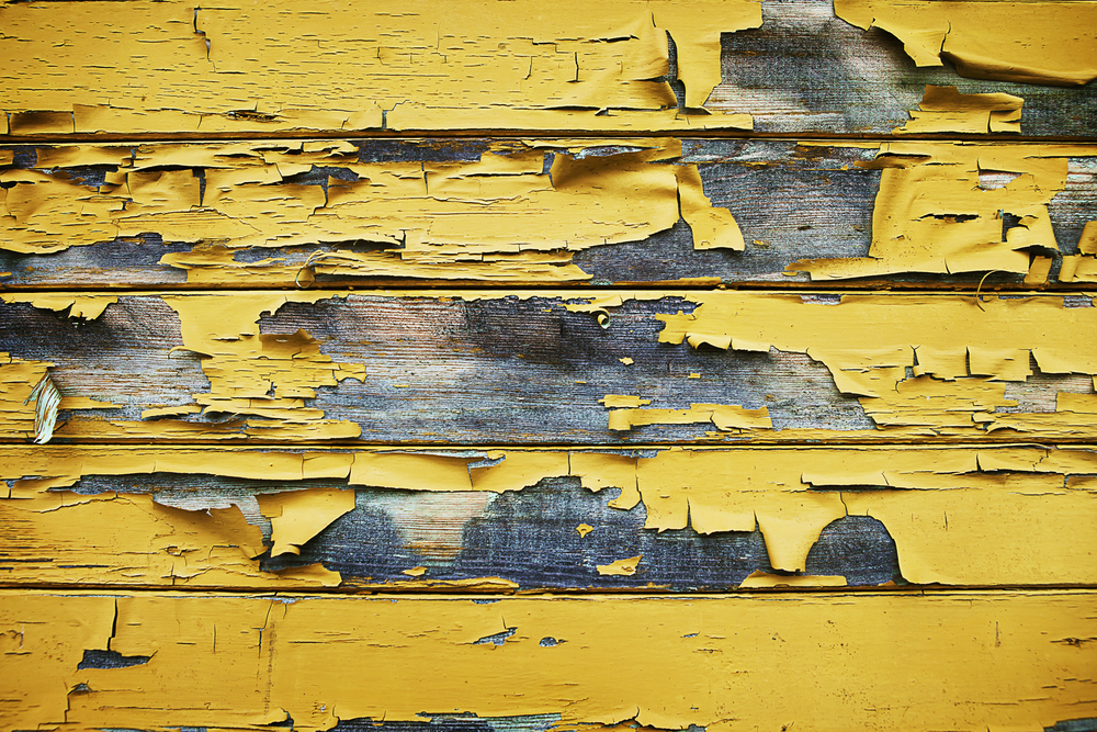 yellow paint peeling off of the side of a house