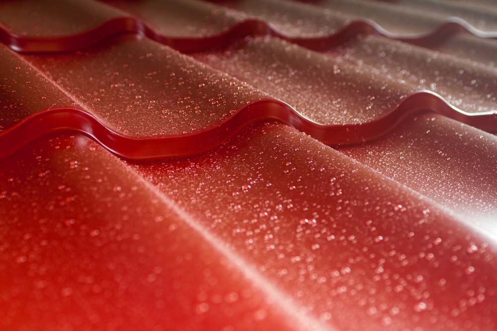 a close-up of a red tile metal roof that is wet from rain