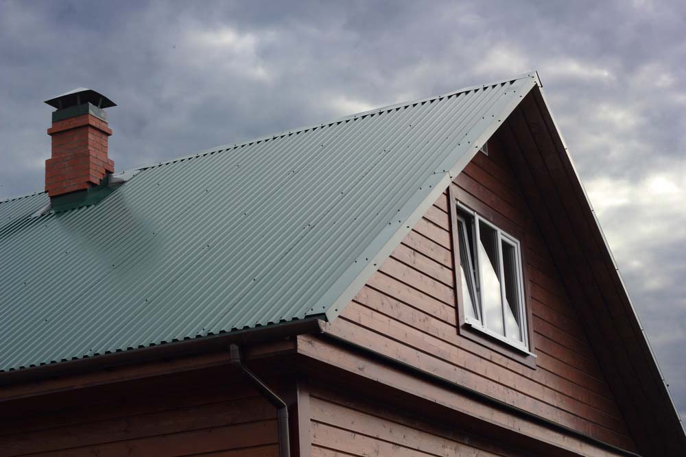 a home with a green metal roof under a stormy sky