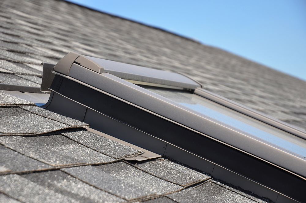 a skylight on a grey shingle roof