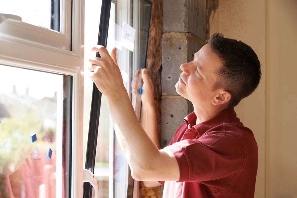 A worker in a red shirt replaces a window.