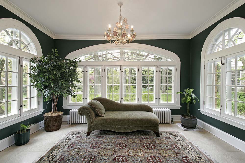 A sunny room with large, white, arched windows on three walls.