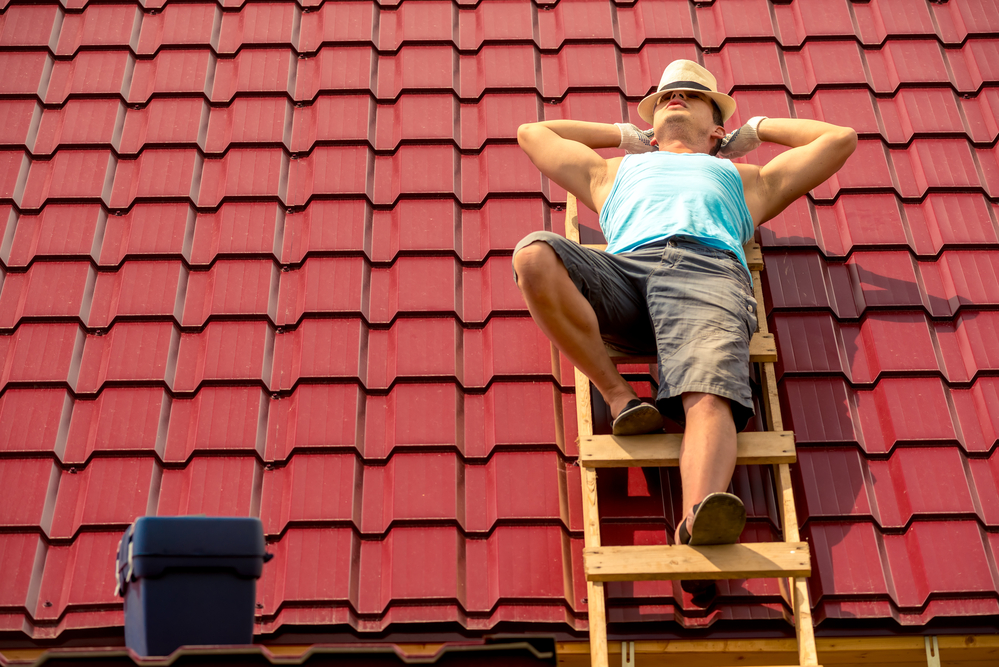 a roofer taking a break lying on a roof on a hot summer day